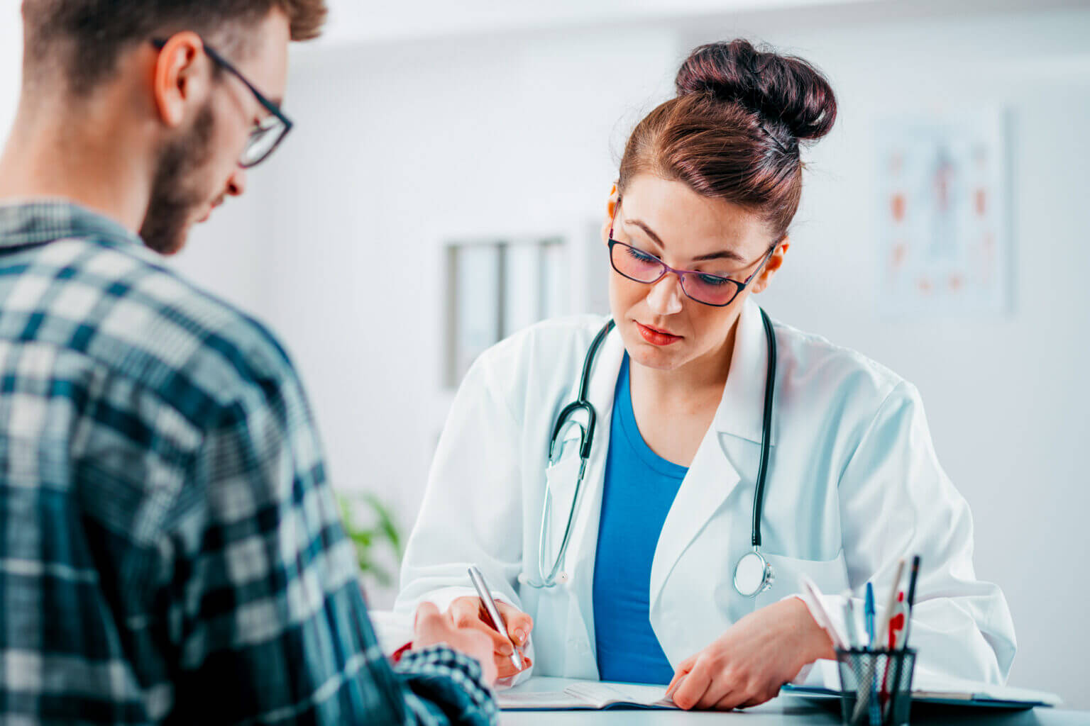 A doctor and a patient review documents together in a medical office.